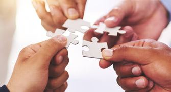 Four people with a jigsaw piece in each hand